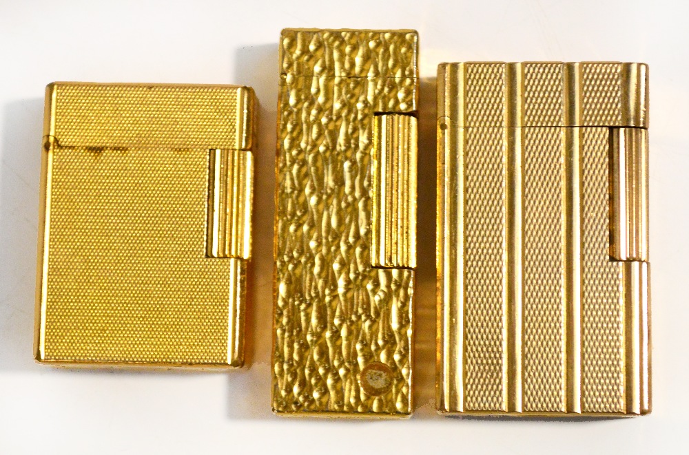 A vintage gold plated Dunhill lighter of textured rectangular form and two gold plated Dupont