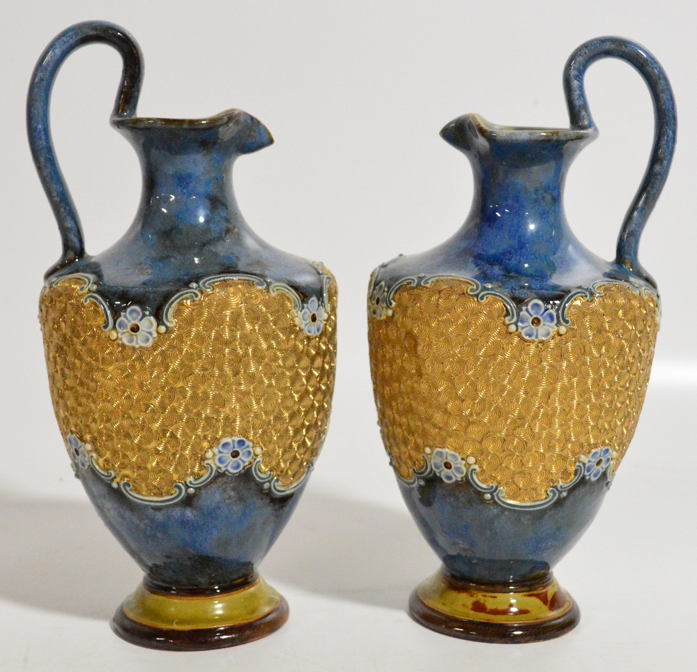 A pair of early 20th century Royal Doulton stoneware ewers, decorated with a band of incised
