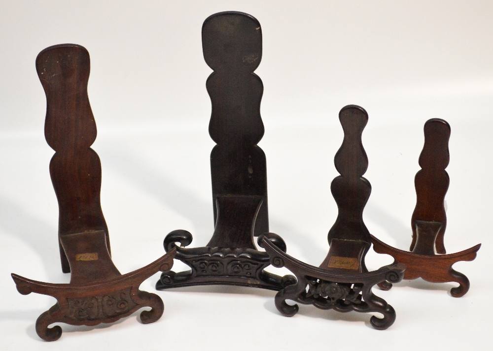 Four 19th century Chinese hardwood plate display stands, each with shaped back and scrolling front