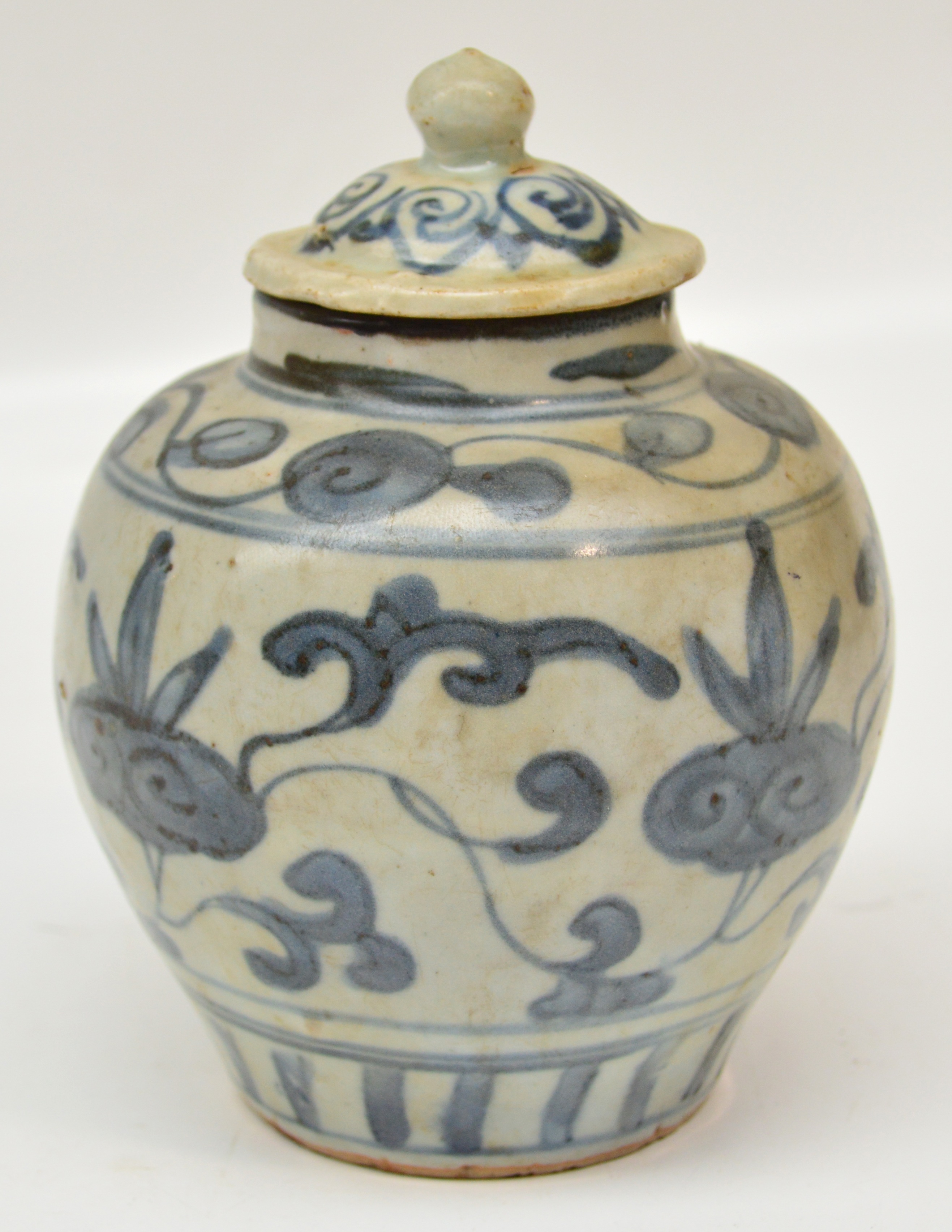 A 16th century Chinese porcelain jar and cover painted in underglaze blue with peony scrolls, height