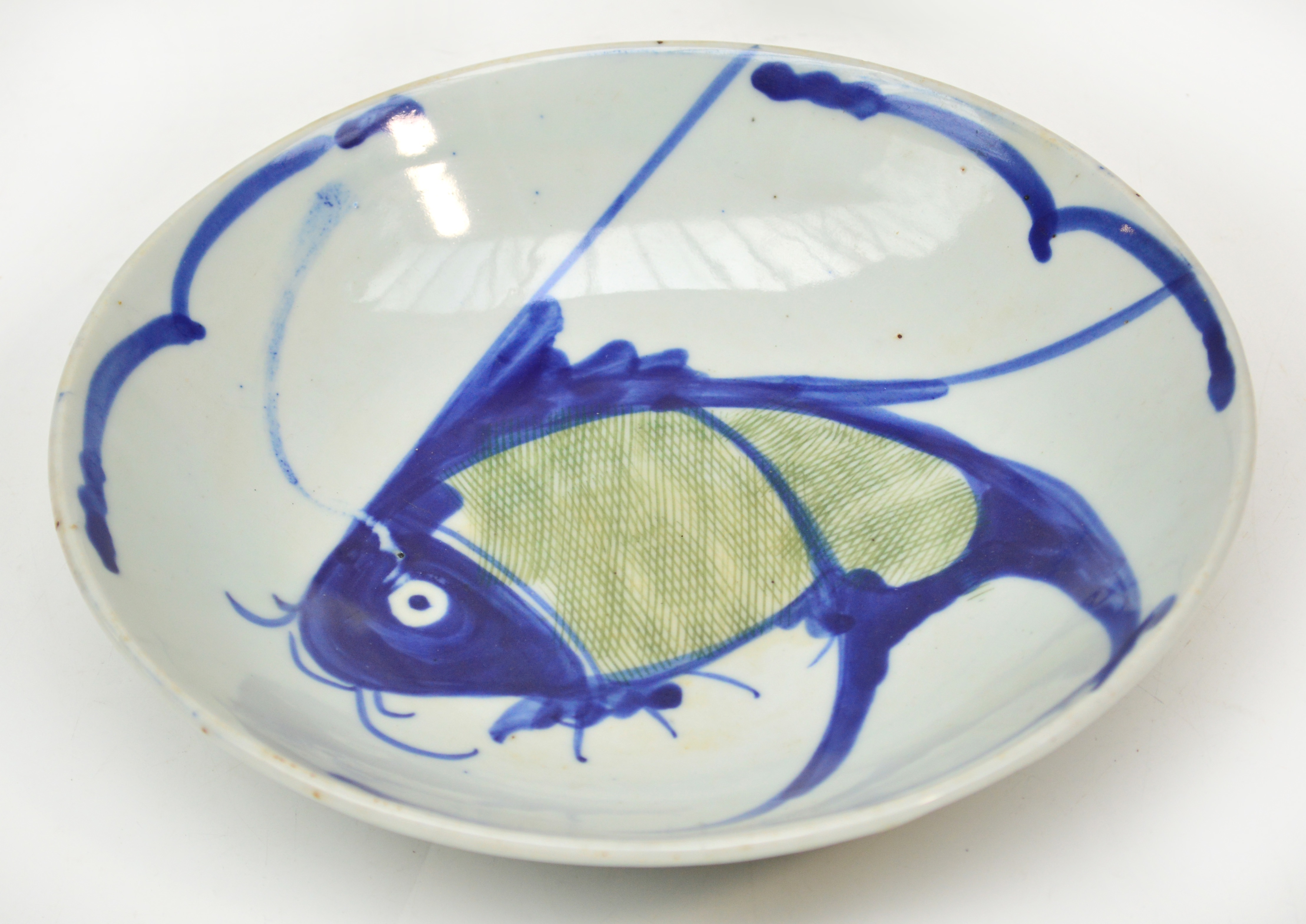 A 19th century Chinese porcelain bowl painted in underglaze blue and green with a fish, diameter