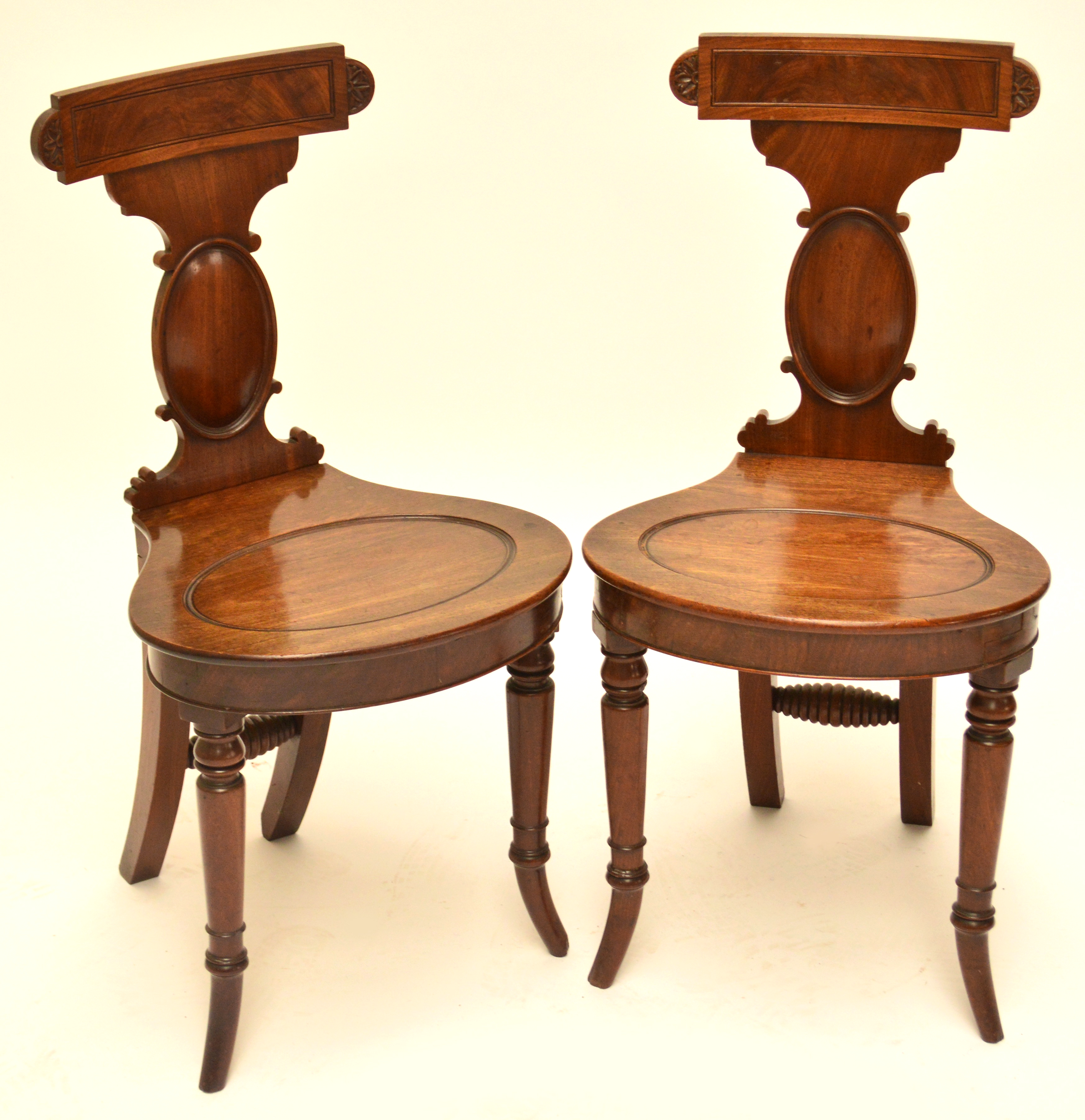 A good pair of Regency mahogany hall chairs, the bar back above oval moulded support, oval seat