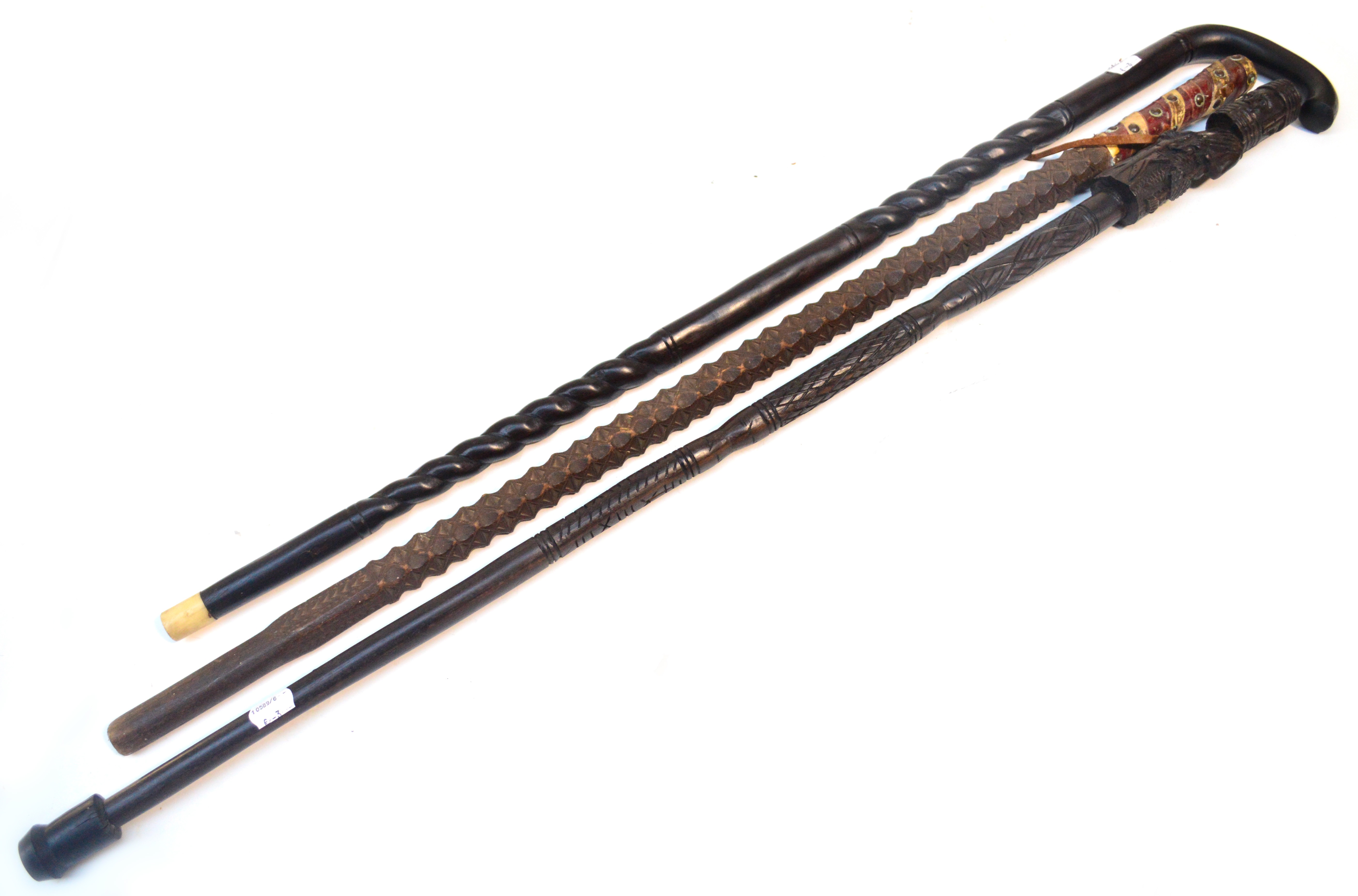 An early 20th century ebonised walking stick, a carved walking stick and a walking cane with incised