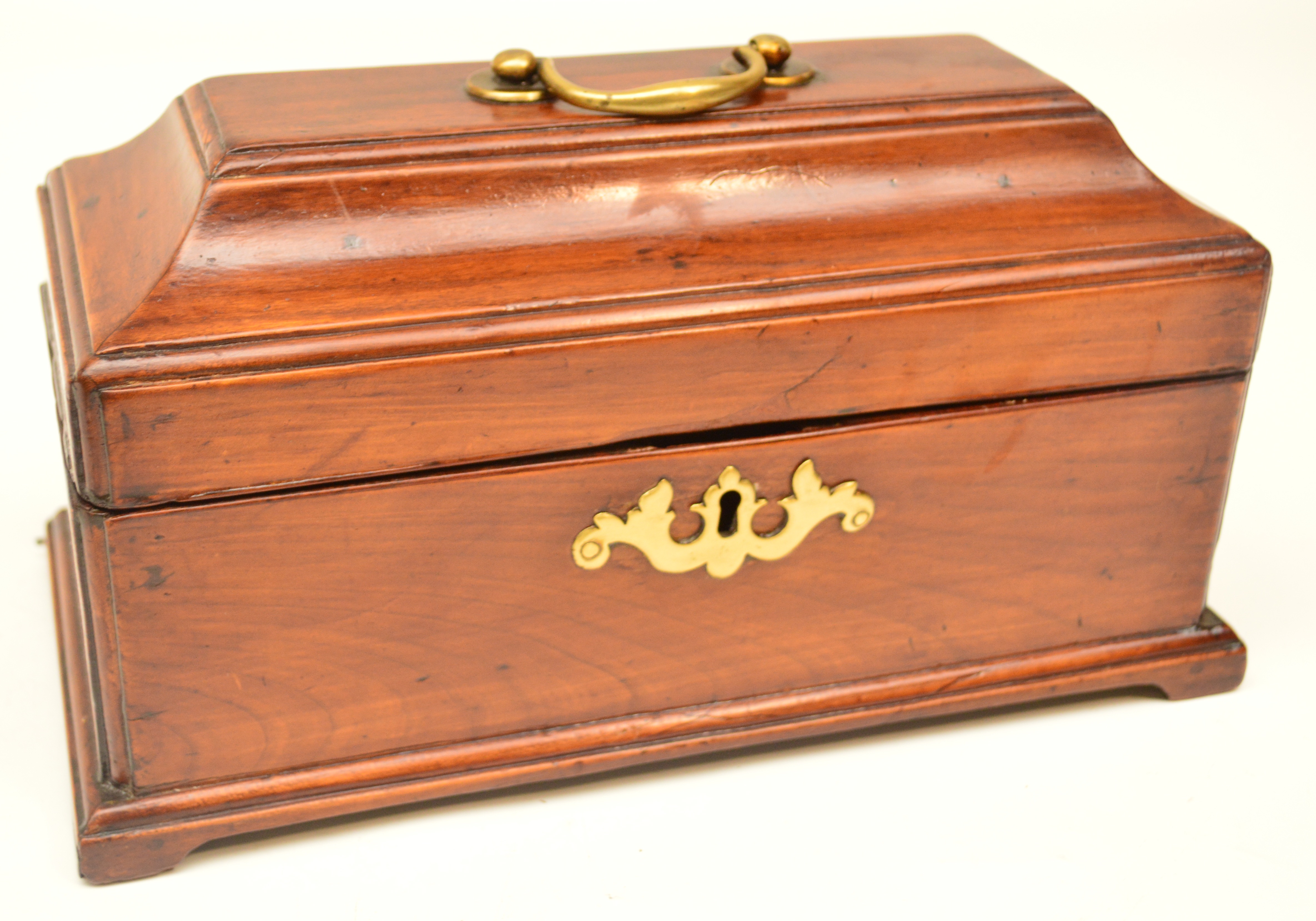 A 19th century mahogany sarcophagus form tea caddy, the hinged lid enclosing three section interior,