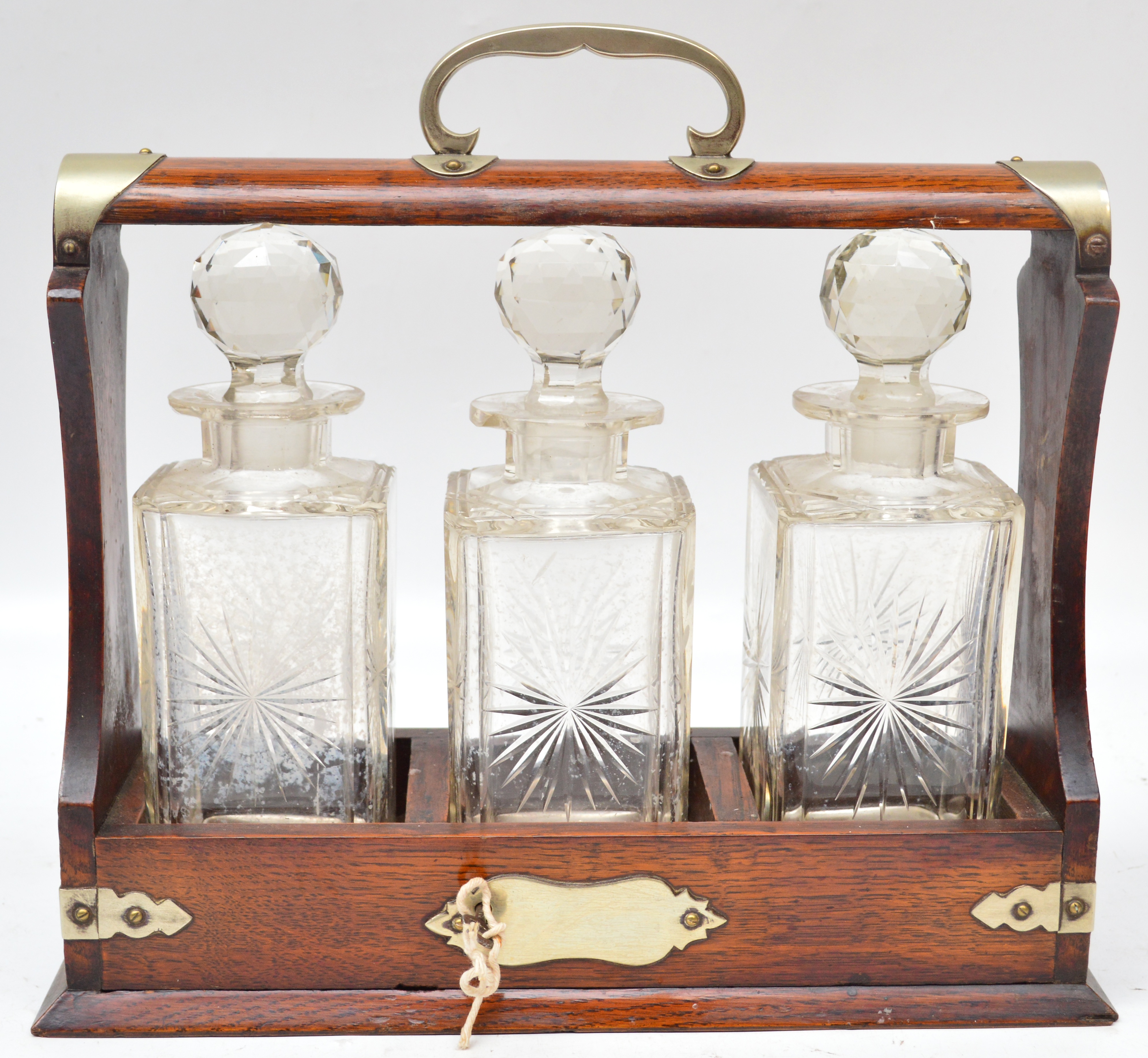 An Edwardian oak and silver plated mounted three bottle tantalus, complete with key. CONDITION