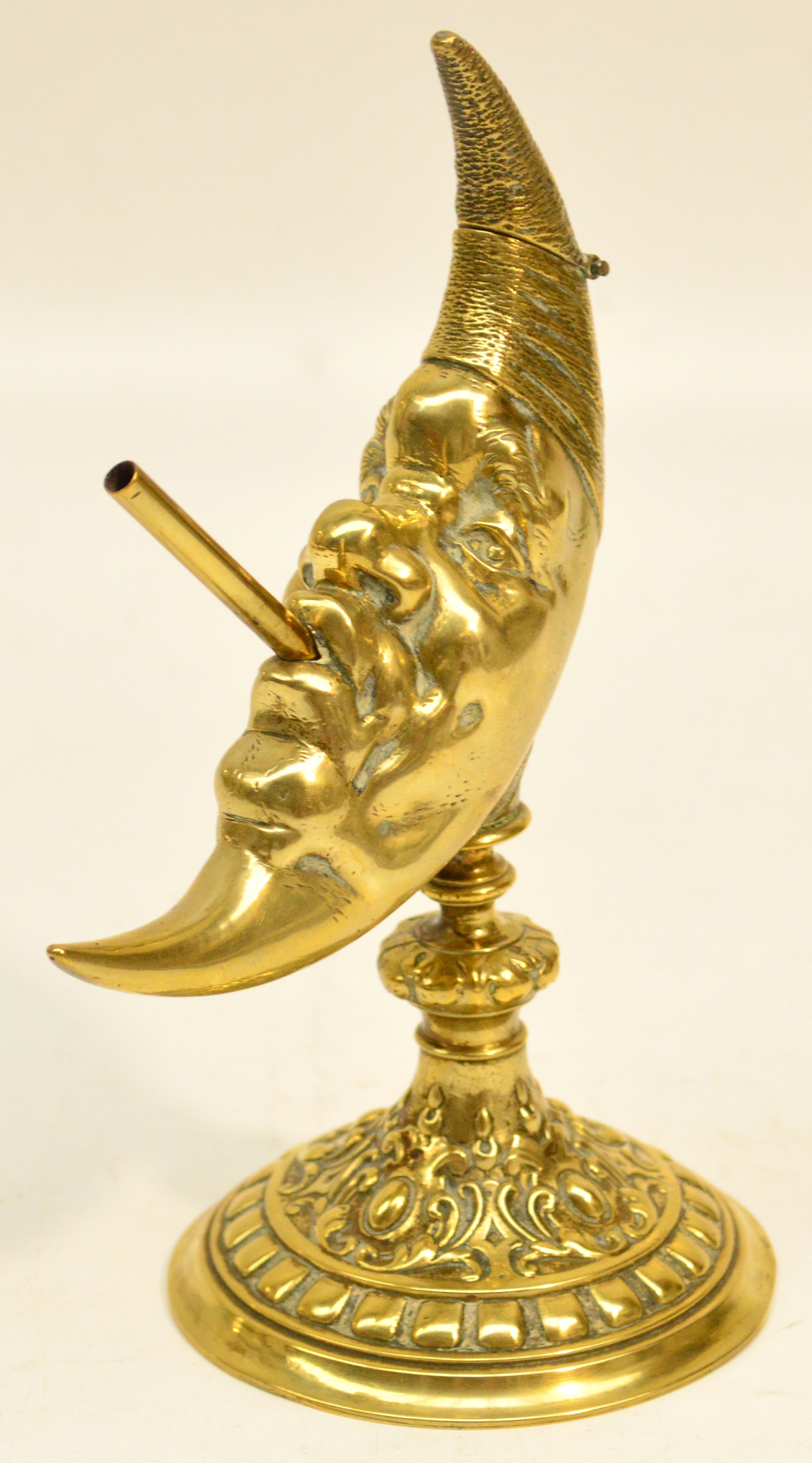 A brass Go-to-bed in the shape of the man in the moon, raised on spreading circular foot, height