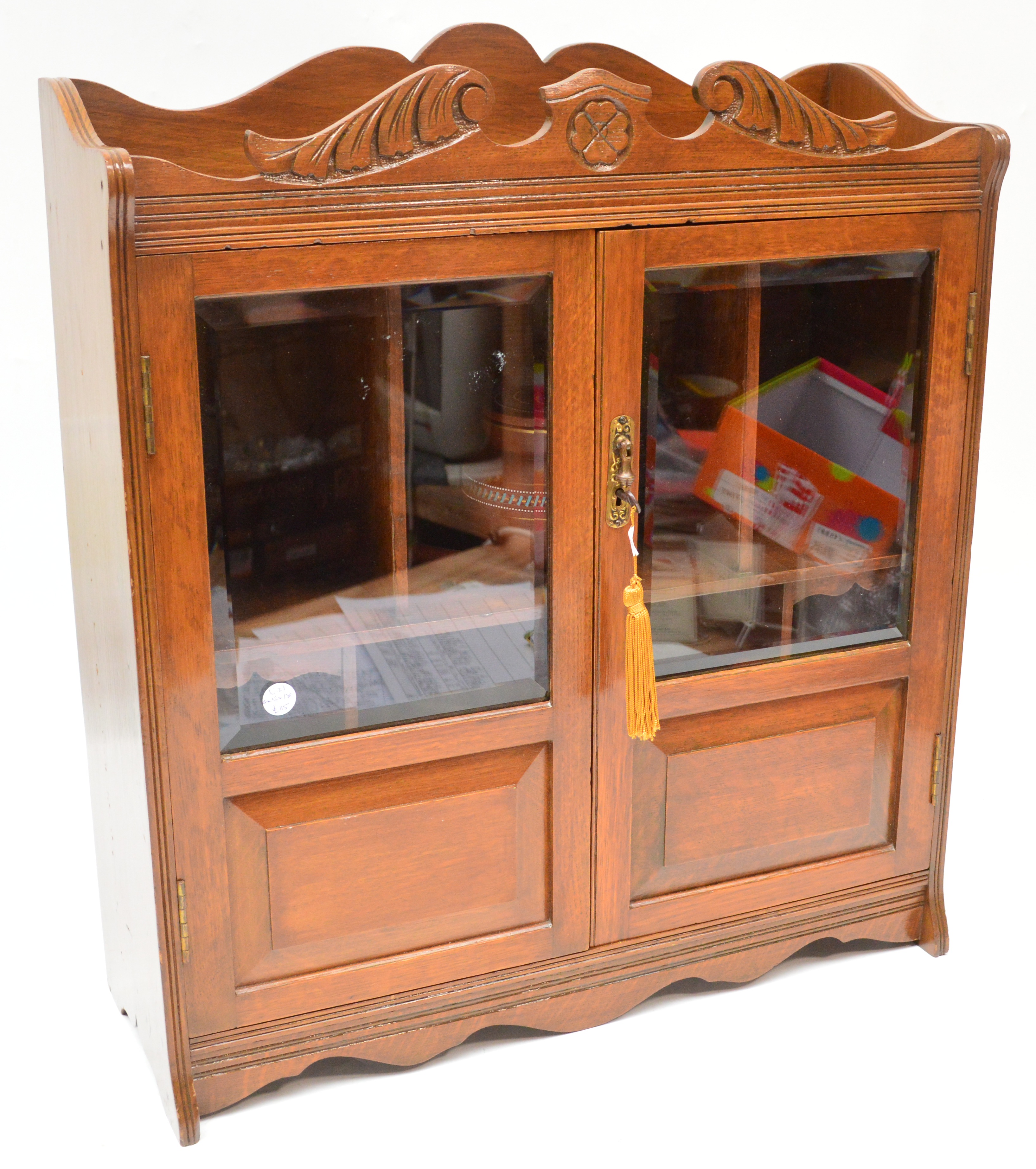 An Edwardian oak smokers cabinet with glazed door enclosing compartments and various accessories,