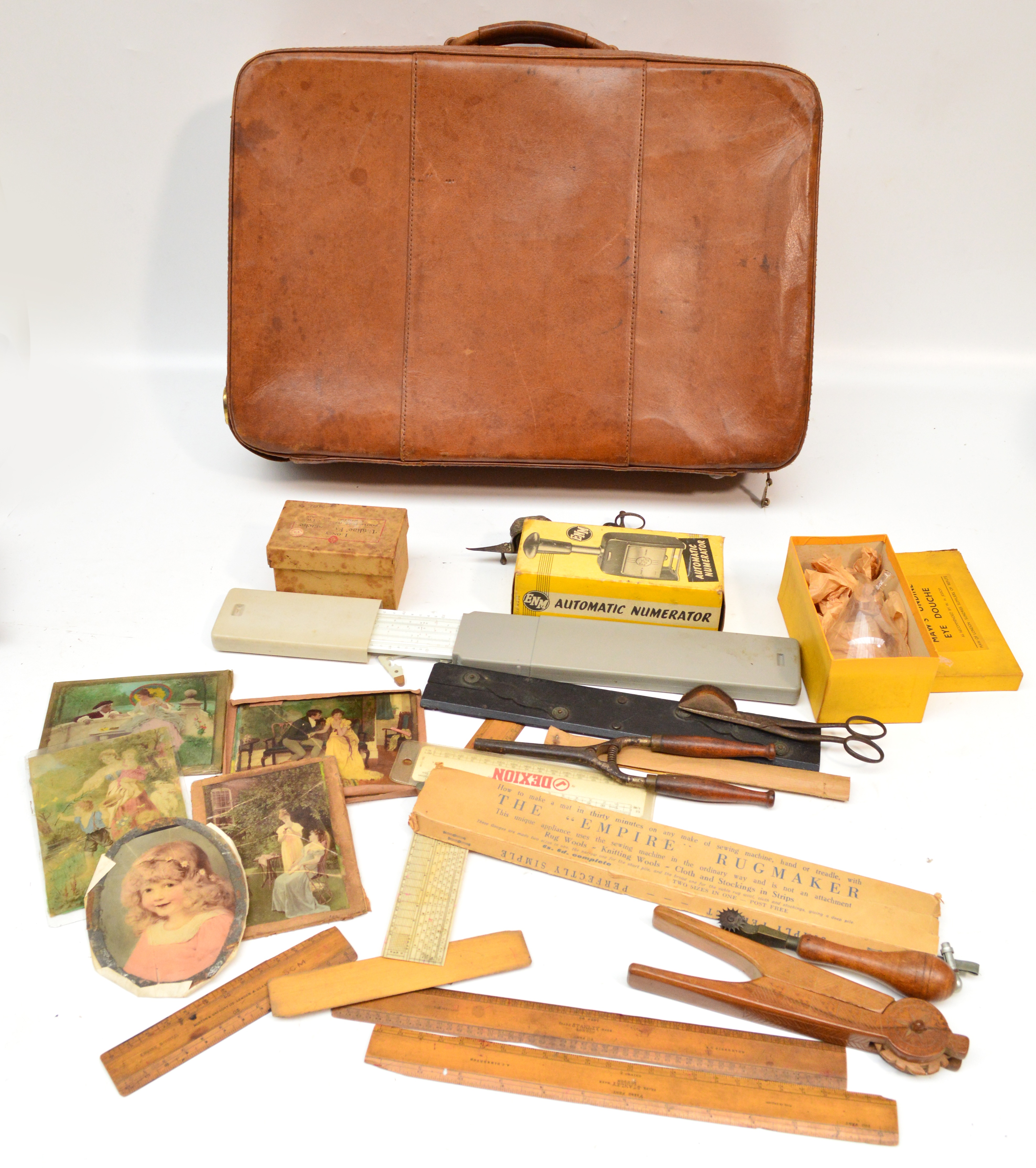 A leather suitcase containing a mixed lot of collectables including a glass eye douche, boxwood