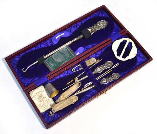 A leather cased sewing set with sterling silver handles, including a large button hook and base