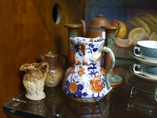 A Pair of Terracotta Candlesticks painted with winged lions, a Terracotta Teapot with enamelled