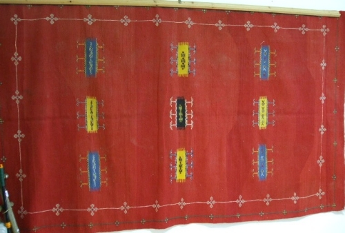 A Machine Made Wool Rug, having geometric patterns on red ground.