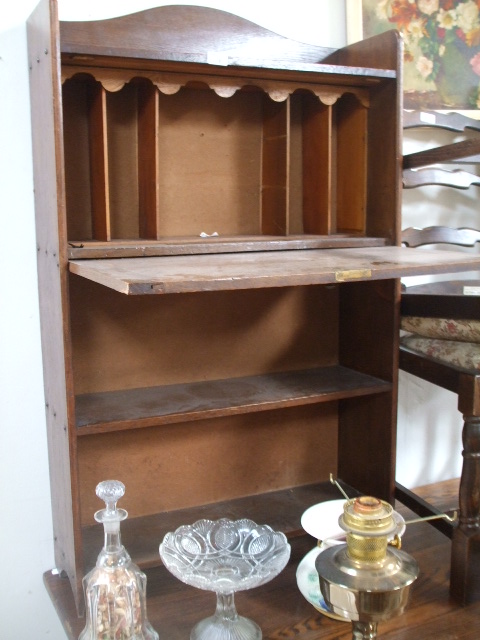 An Oak Bureau, having fall-flap upper section revealing fitted interior, above shelved section.