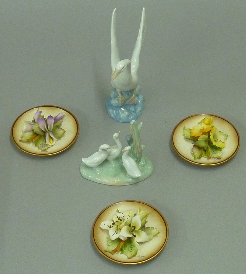 3 floral Capodimonte circular wall plaques and 2 Nao figurines. (5)