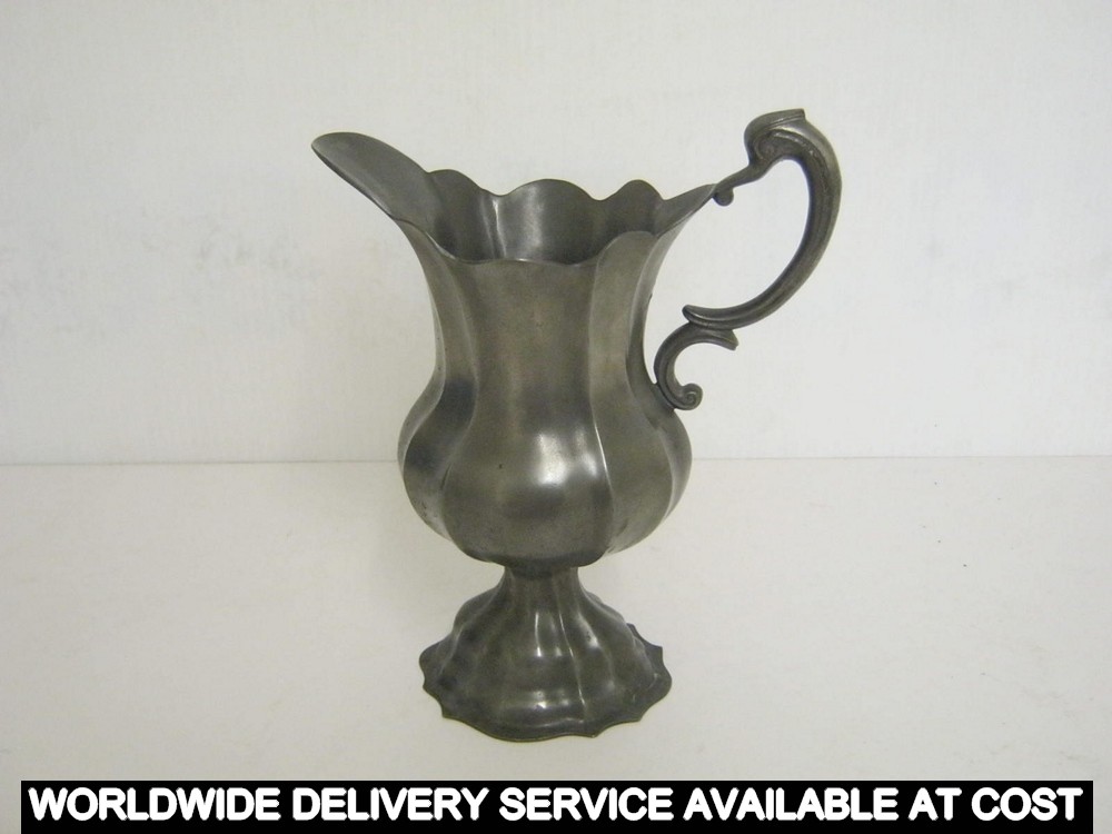 A pewter jug with serpent handle on a raised foot