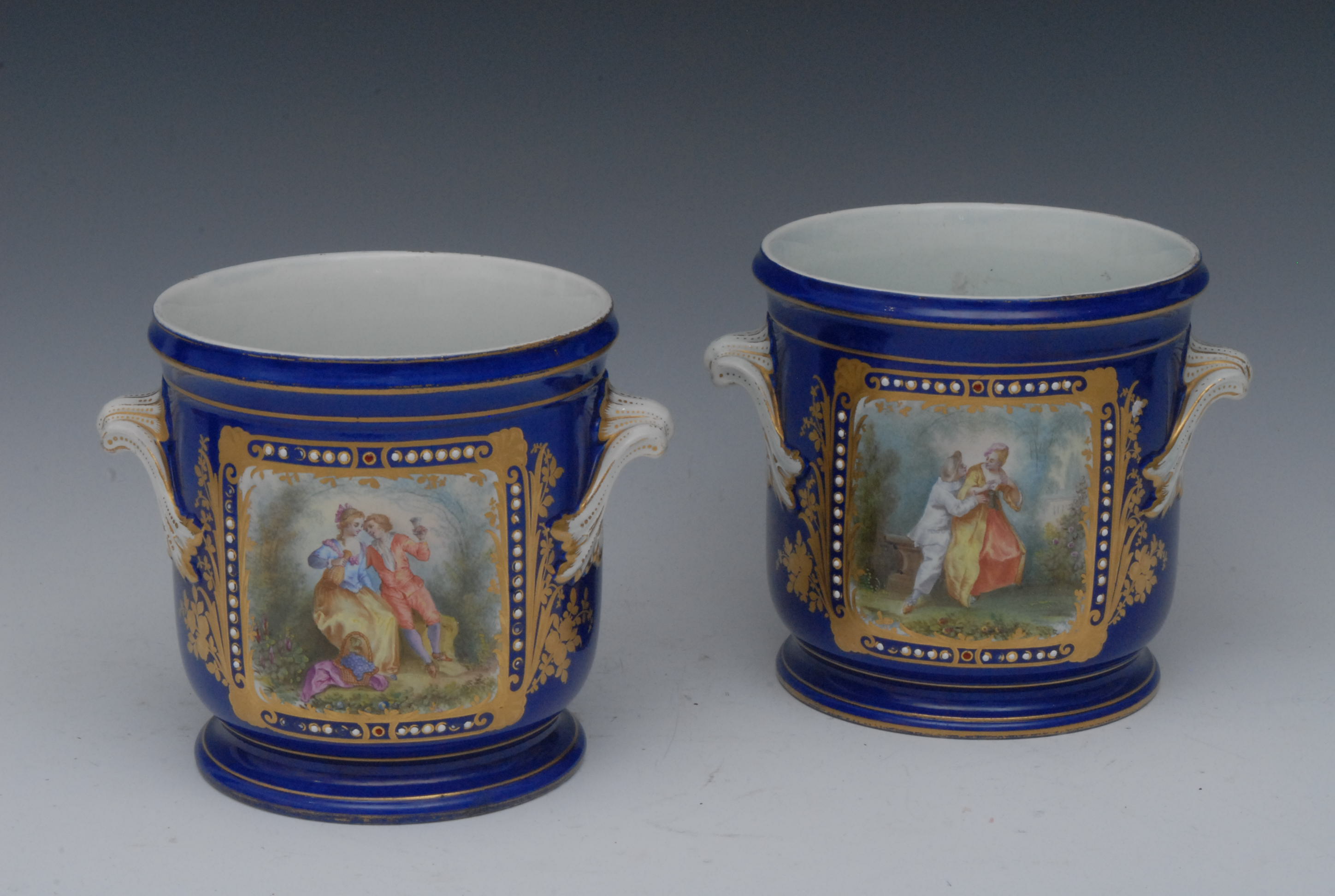 A pair of French cache pots, in the manner of Sevres, decorated with rounded rectangular reserves