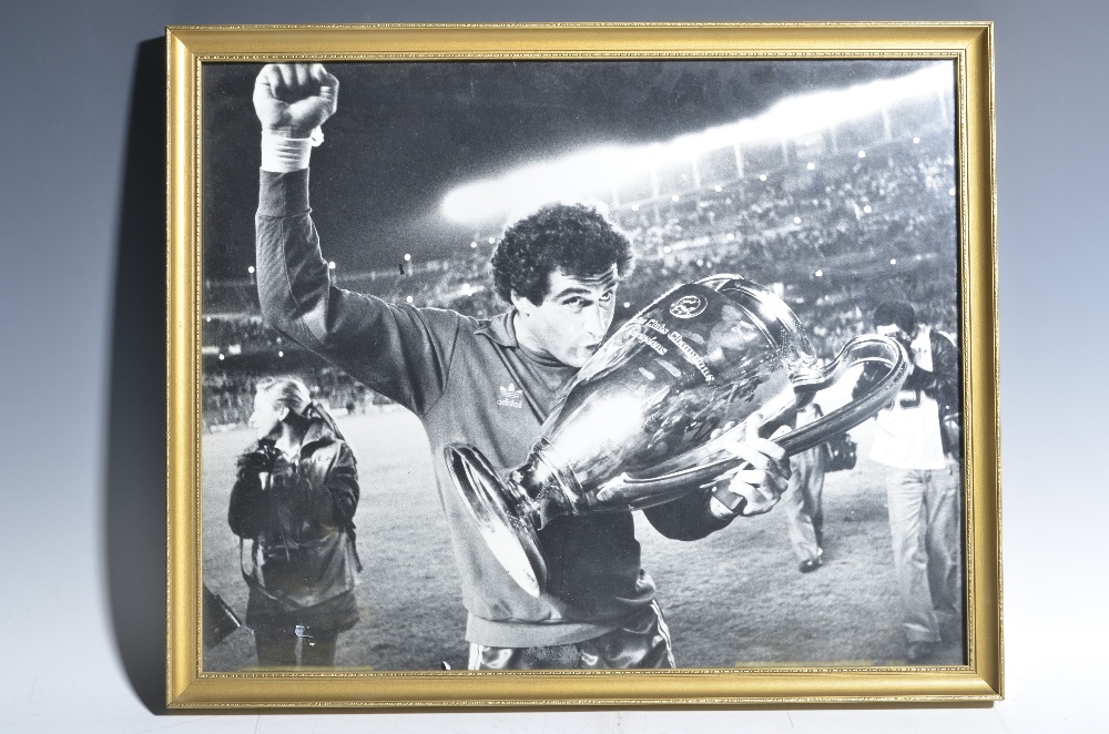 A black and white photograph of Peter Shilton kissing the European Cup, arm raised, in the Stadium
