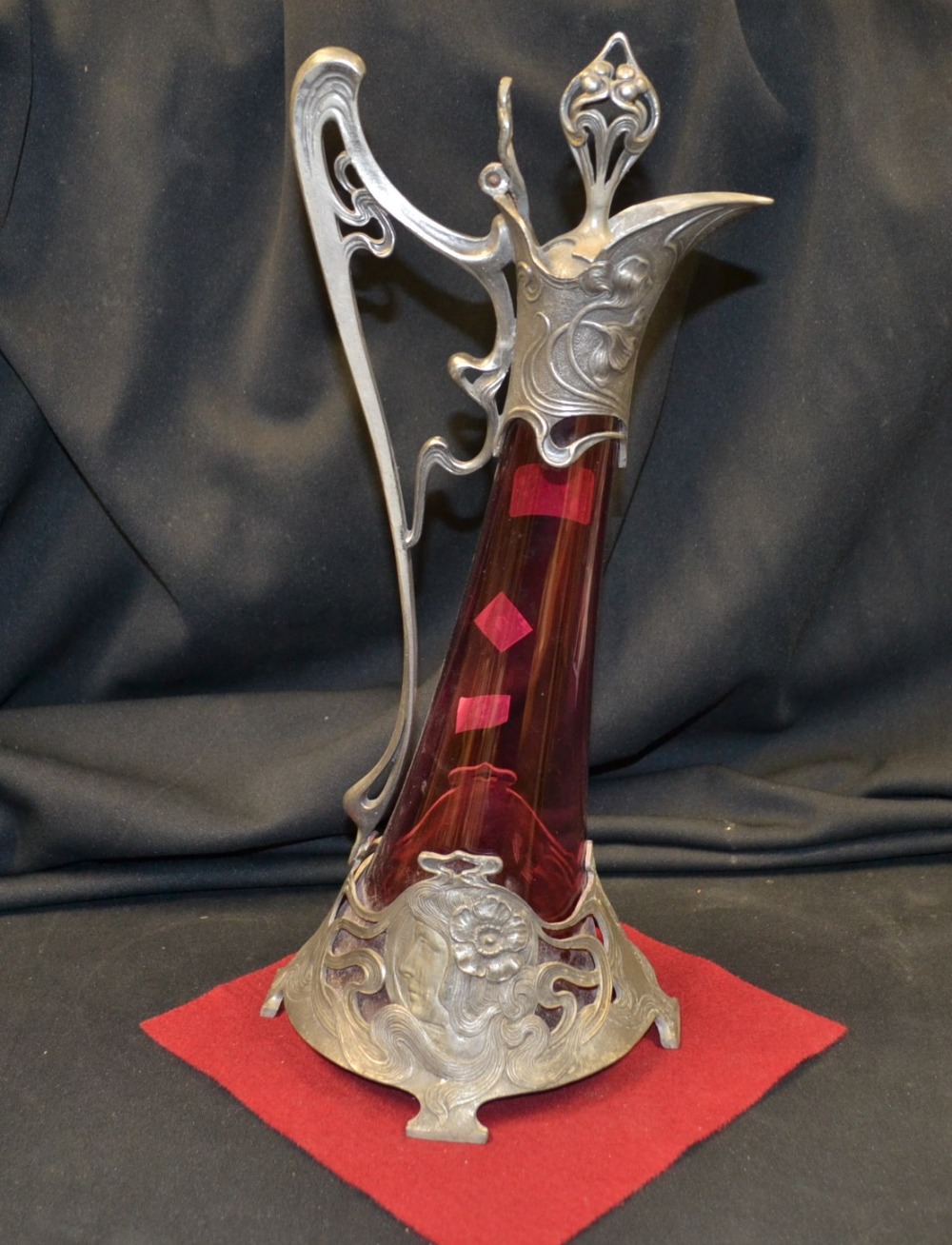A W.M.F. style Jugendstil pewter claret jug,  flared cranberry glass body, pewter mounts cast and