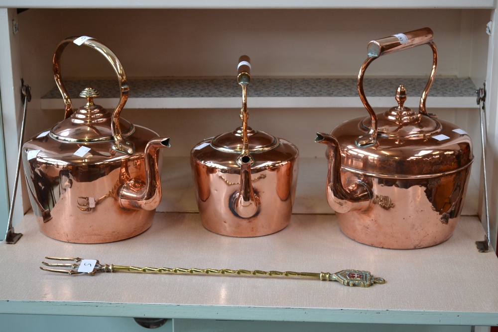 A Victorian copper kettle, acorn finial; another similar; another smaller with acorn knop; a brass