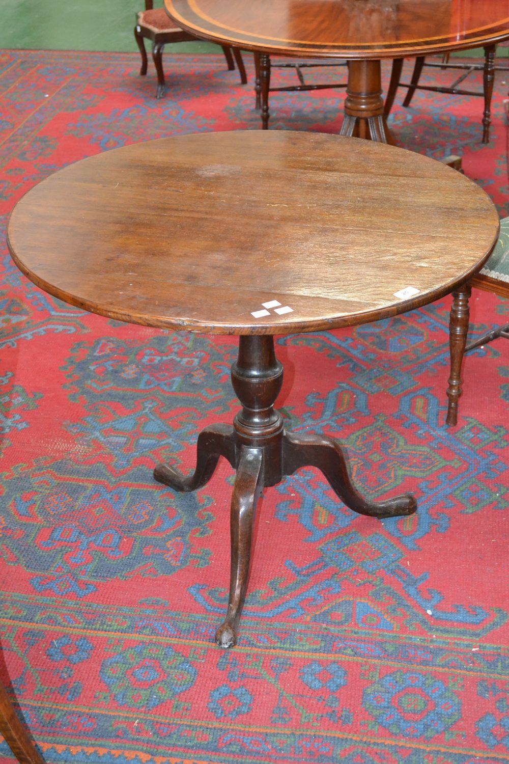 A Georgian oak tilt top tripod occasional table, circular top, baluster column, cabriole legs, pad