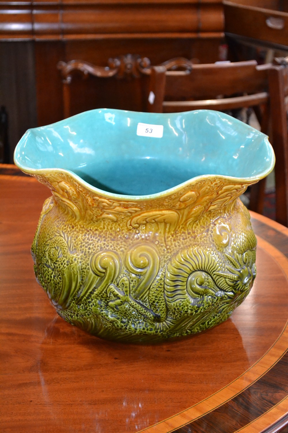 An Ault pottery jardiniere, in relief with dragons and waves on a green and yellow stippled