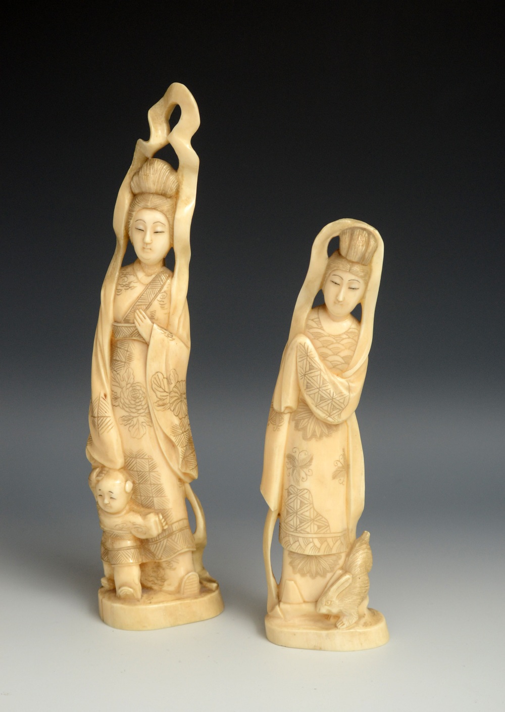 A Japanese ivory okimono, carved as a geisha, she stands, a young boy at her side, oval base, 23cm
