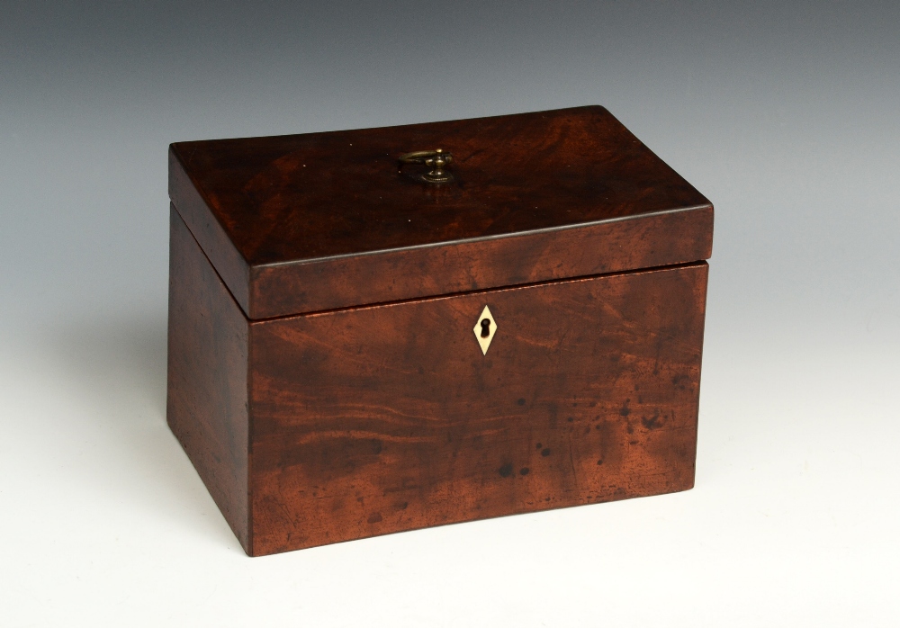 A George III mahogany rectangular tea caddy, hinged cover with brass axehead handle, enclosing a