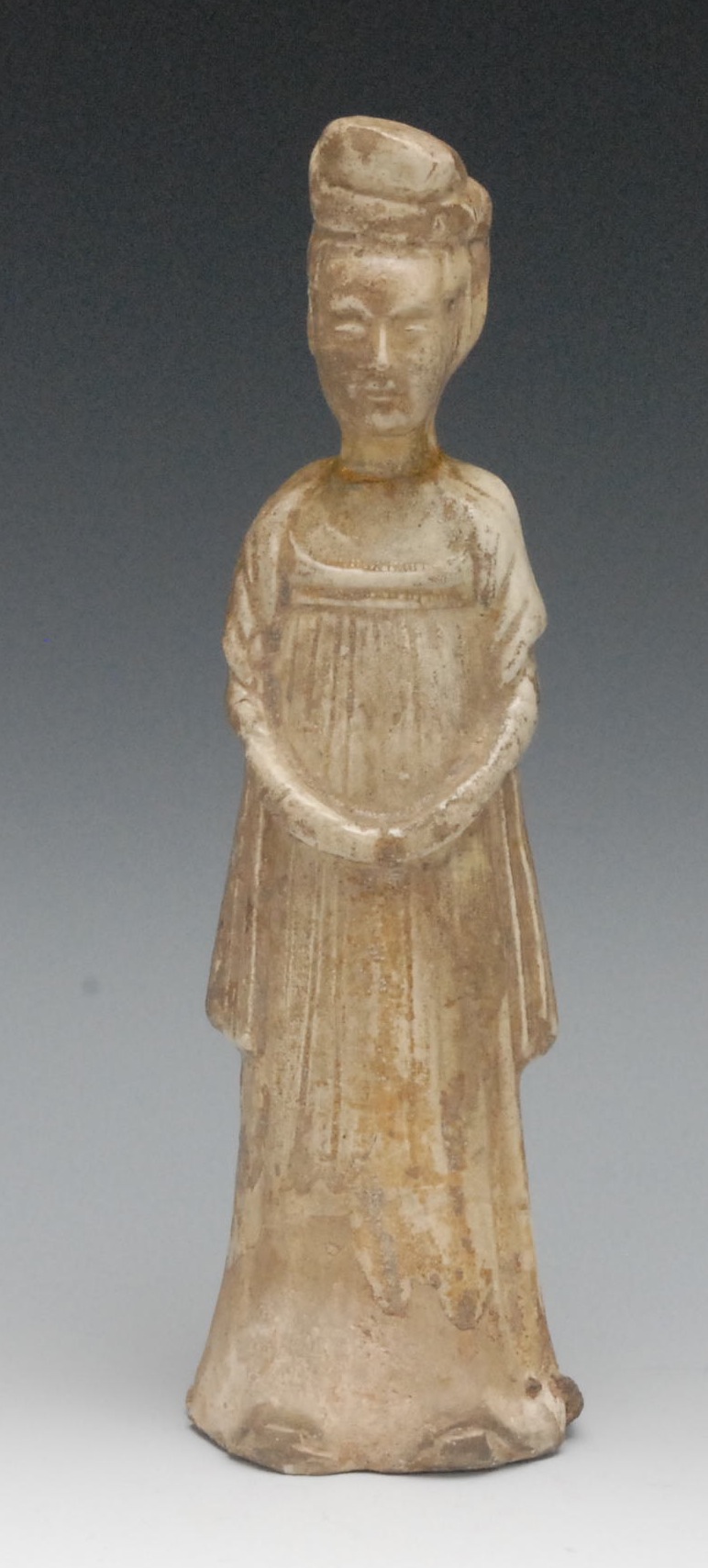 A Chinese pale glazed terracotta figure, of a female attendant, she stands, with hands clasped