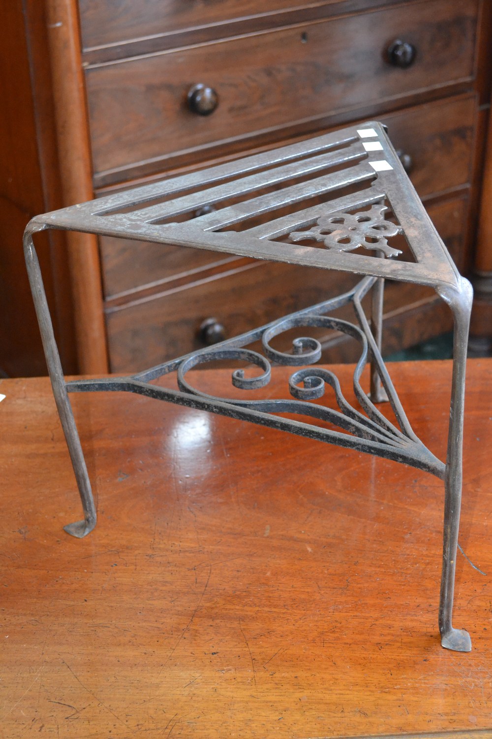 A 19th century steel footman, of triangular shape, the under tier with scrolls, 34cm high