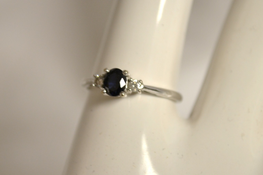 A 9ct. white gold ring, the central sapphire flanked  by two diamonds