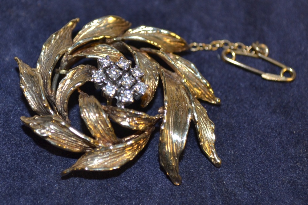A diamond lady`s brooch, centred by nine claw set stones, gold coloured metal mount as a cluster