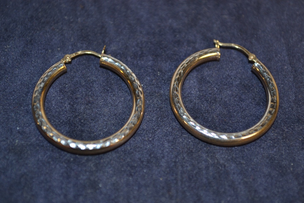 A pair of white and yellow gold coloured metal earrings