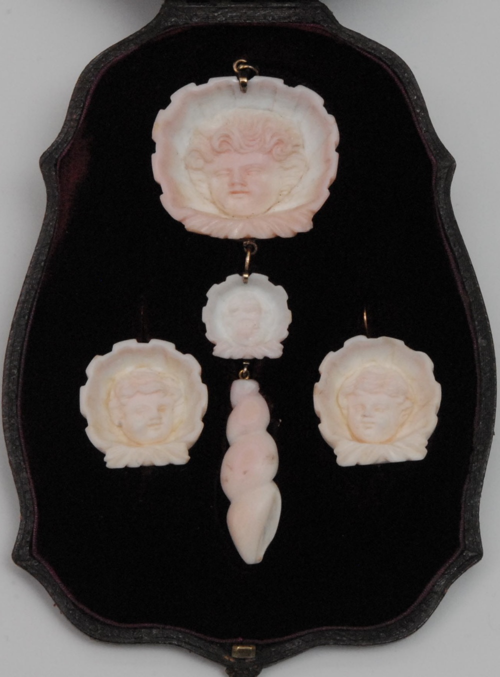A Victorian conch shell cameo suite, comprising a pendant and a pair of earrings, each carved with a