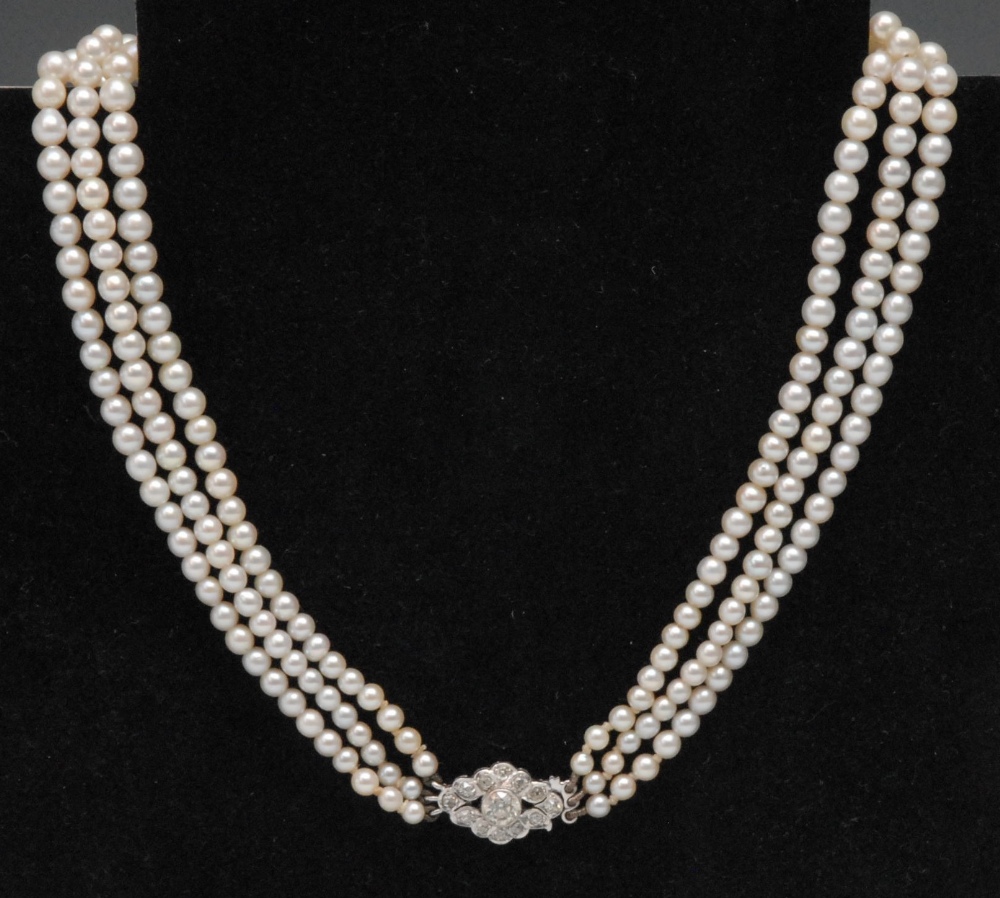 An Art Deco diamond set three row graduated freshwater pearl choker, the lozenge shaped clasp colett