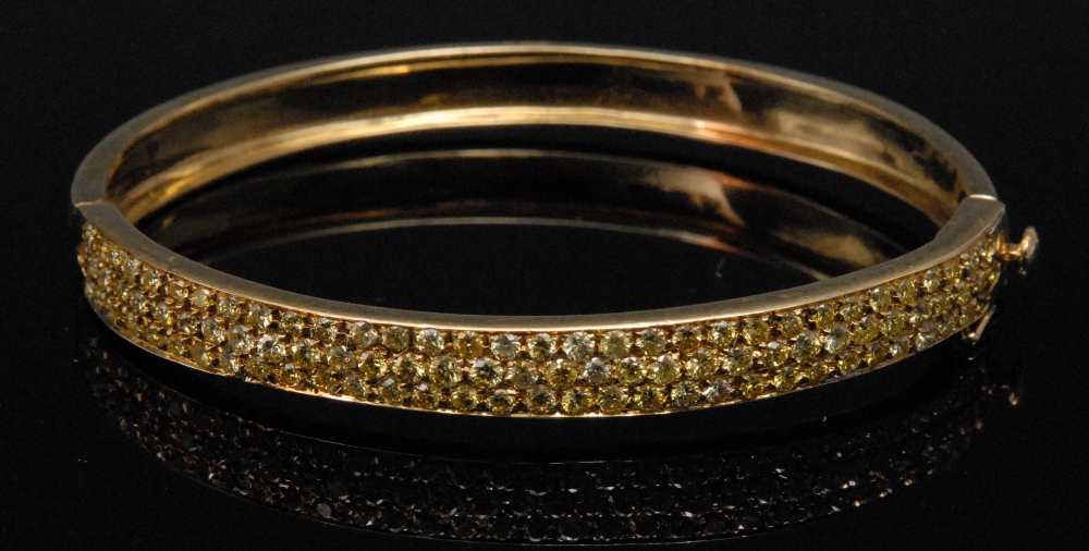 A lady`s  yellow diamond hinged bangle, set with three rows of stones of natural colour, approx