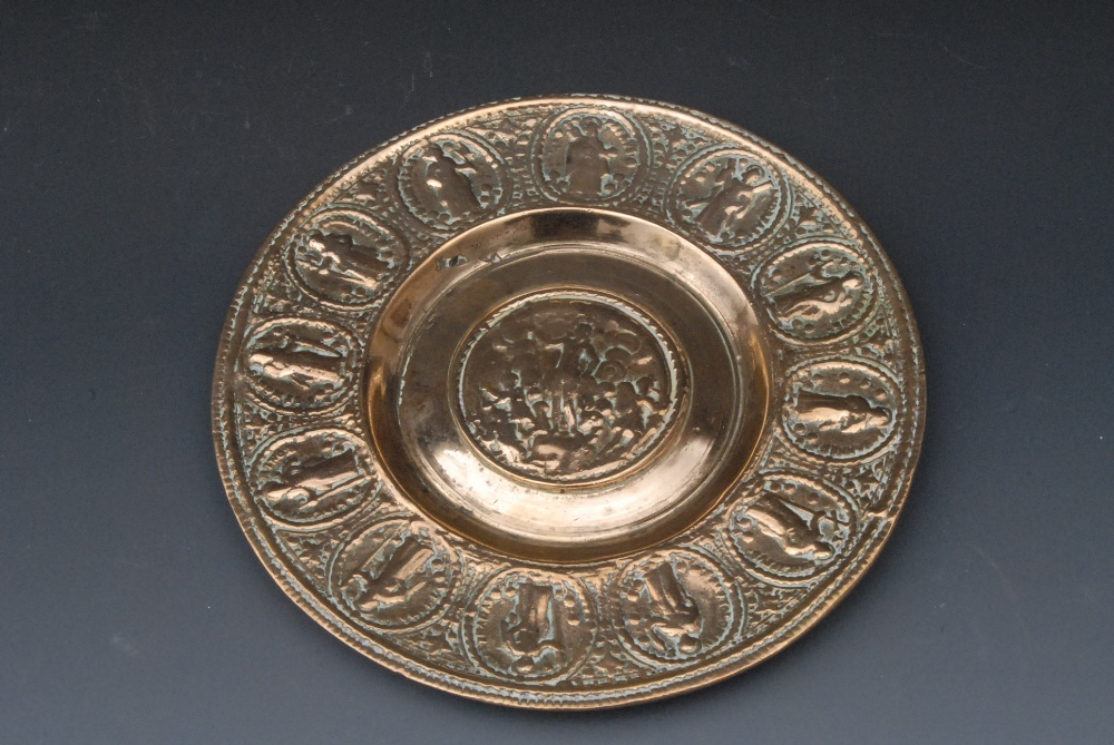 A 19th century brass paten, the field cast with Christ, the rim with twelve apostles, 18.5cm diam