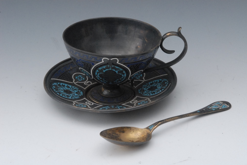 A 19th century champleve enamel tea cup, saucer and spoon, probably Russian, decorated in tones of