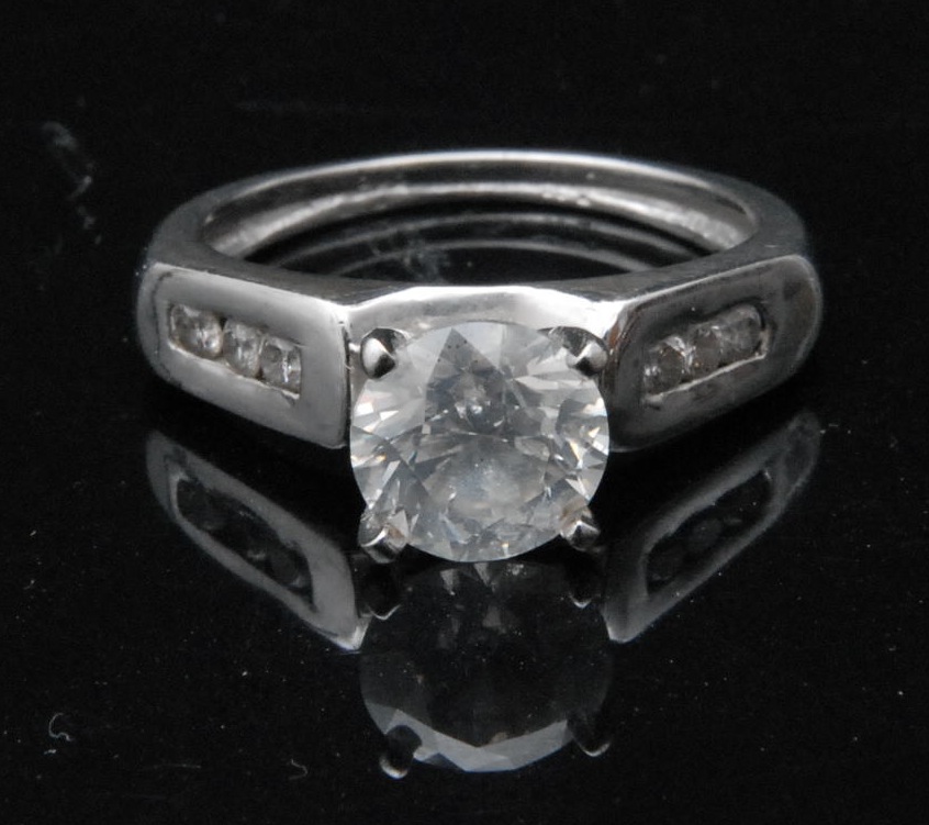 A solitaire diamond ring, brilliant-cut stone, three stones to each shoulder, 14ct white gold shank,