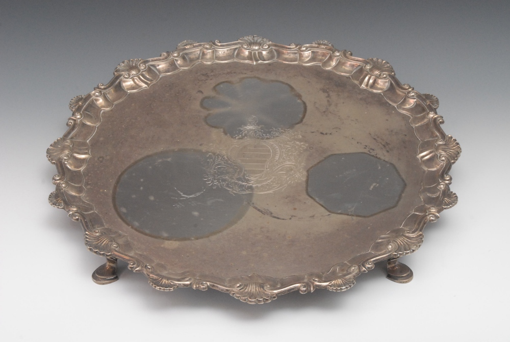 A George III shaped circular salver, engraved crest to centre, shell and scroll border, hoof feet,