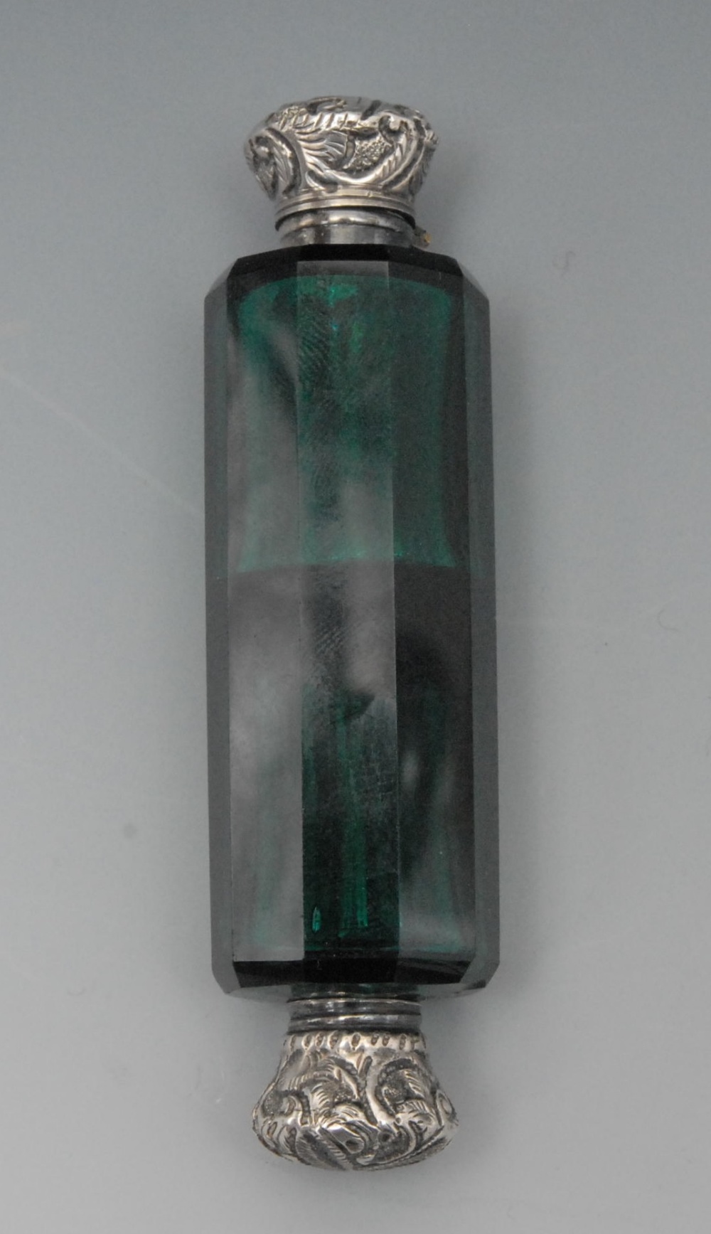 A 19th century silver coloured metal mounted emerald glass double ended scent bottle, hinged and