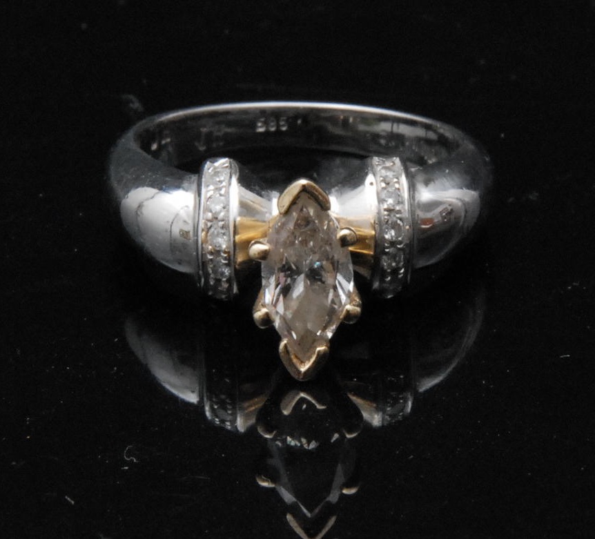 A solitaire diamond ring, navettte-cut stone, six chips to banded shoulders, 14ct white gold