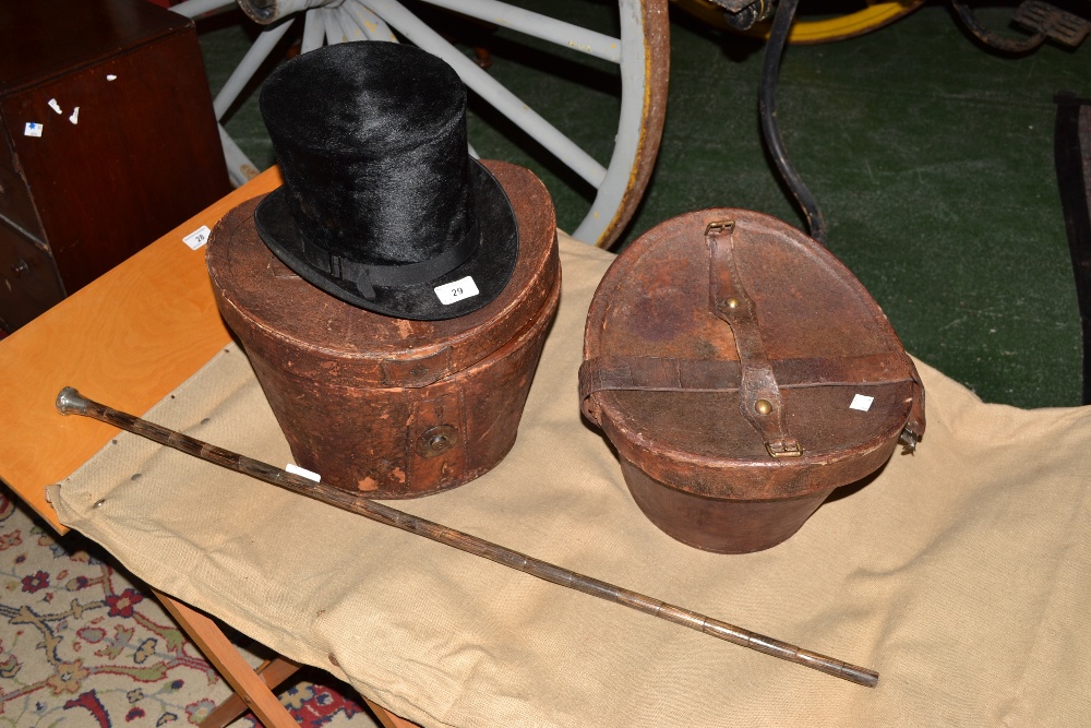 Two leather top hat boxes with one top hat and a silver topped walking cane