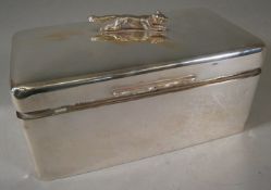 A George V silver cigarette box surmounted by a fox,17.5cm wide.