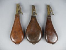 Three leather and brass shot flasks, of typical bag form, each with adjustable lever measure. (3)