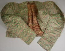 An South East Asian silk jacket. decorated with figures hunting with dogs to a green ground.