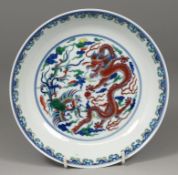 A Chinese doucai saucer dish painted with a five-clawed dragon and phoenix amongst foliage and