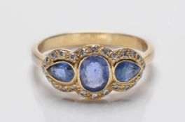A sapphire and diamond mounted triple cluster ring with central oval sapphire between pear-shaped