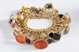 A 9ct gold hollow curb-link bracelet with twenty seven fob seals and one spherical pendant attached,