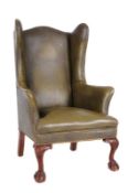 A carved mahogany and upholstered wing frame armchair in the Georgian taste, fully upholstered in