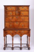 An antique walnut and oak crossbanded chest on stand, the upper part with a moulded cornice,