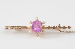 A pink sapphire and diamond bar broochwith central ‘native-cut’ cushion-shaped pink sapphire